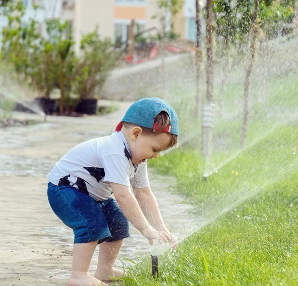 Kid playing at the sprinkler